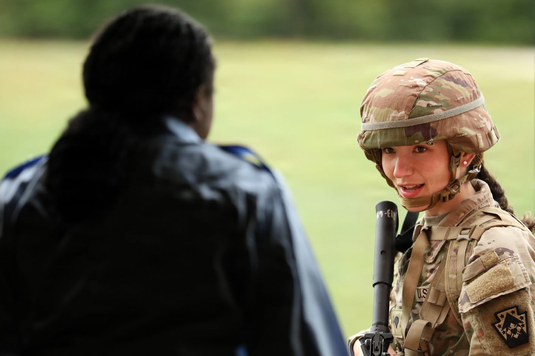 Soldier in camo gear talking to another person. Soldier in camo gear talking to another person.