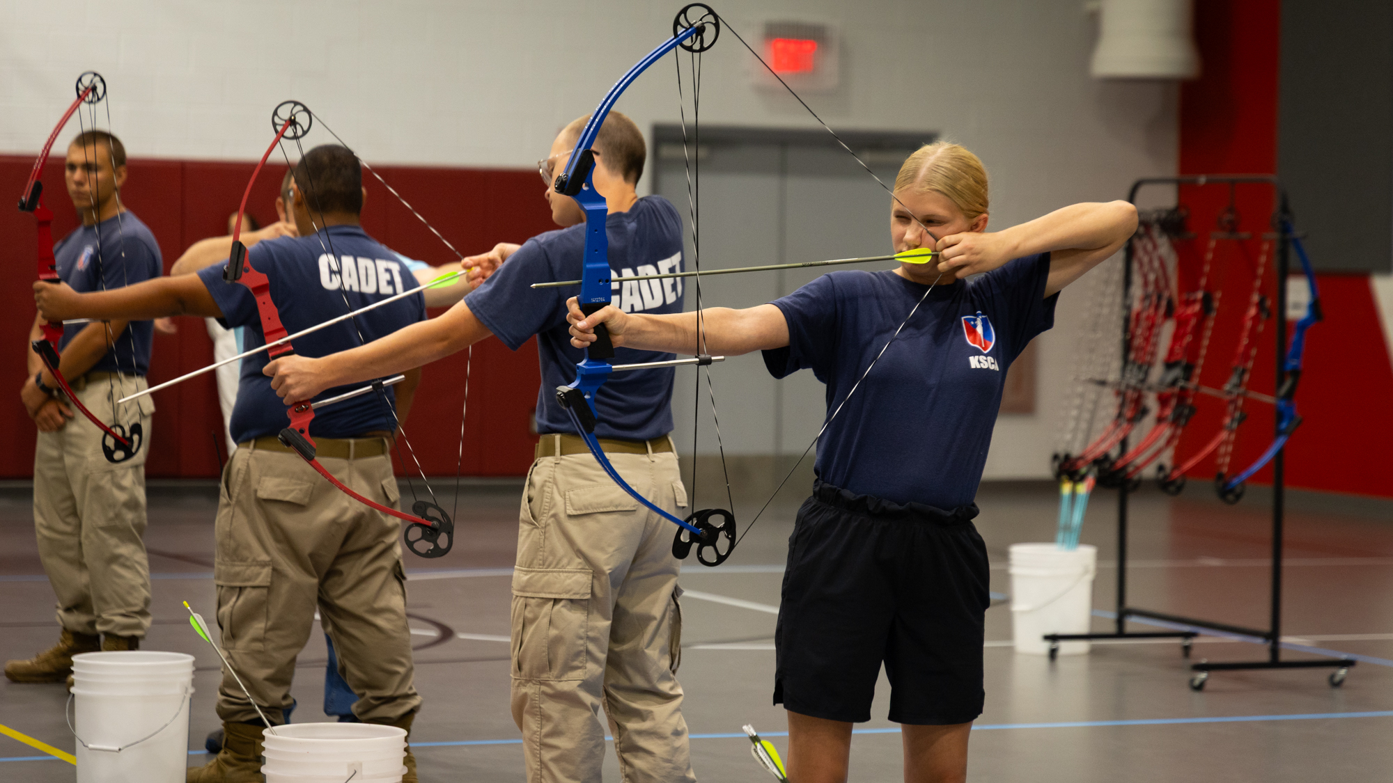 Cadets practice archery indoors, aiming arrows. Cadets practice archery indoors, aiming arrows.